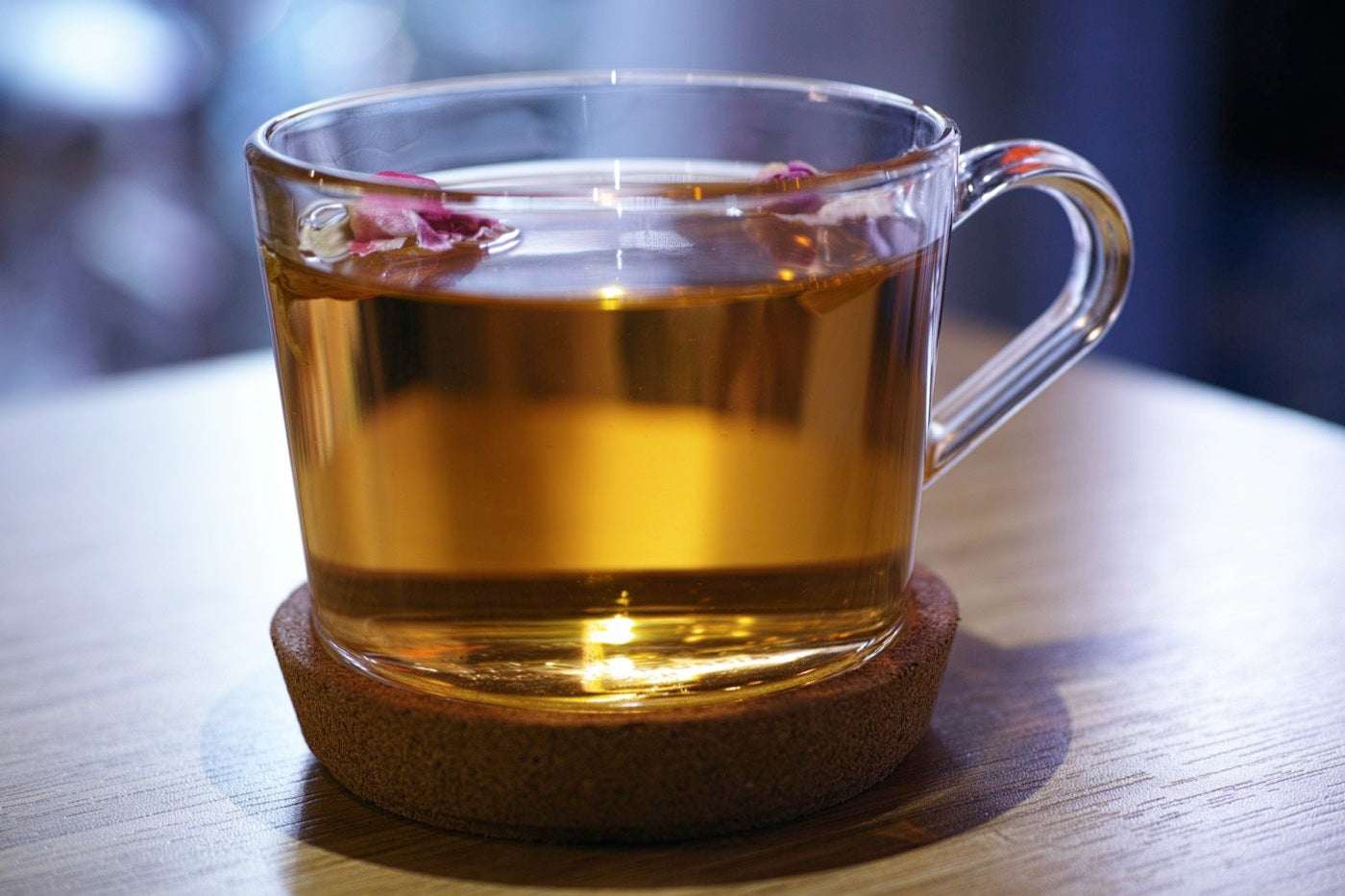 Glass cup of tea on a wooden coaster