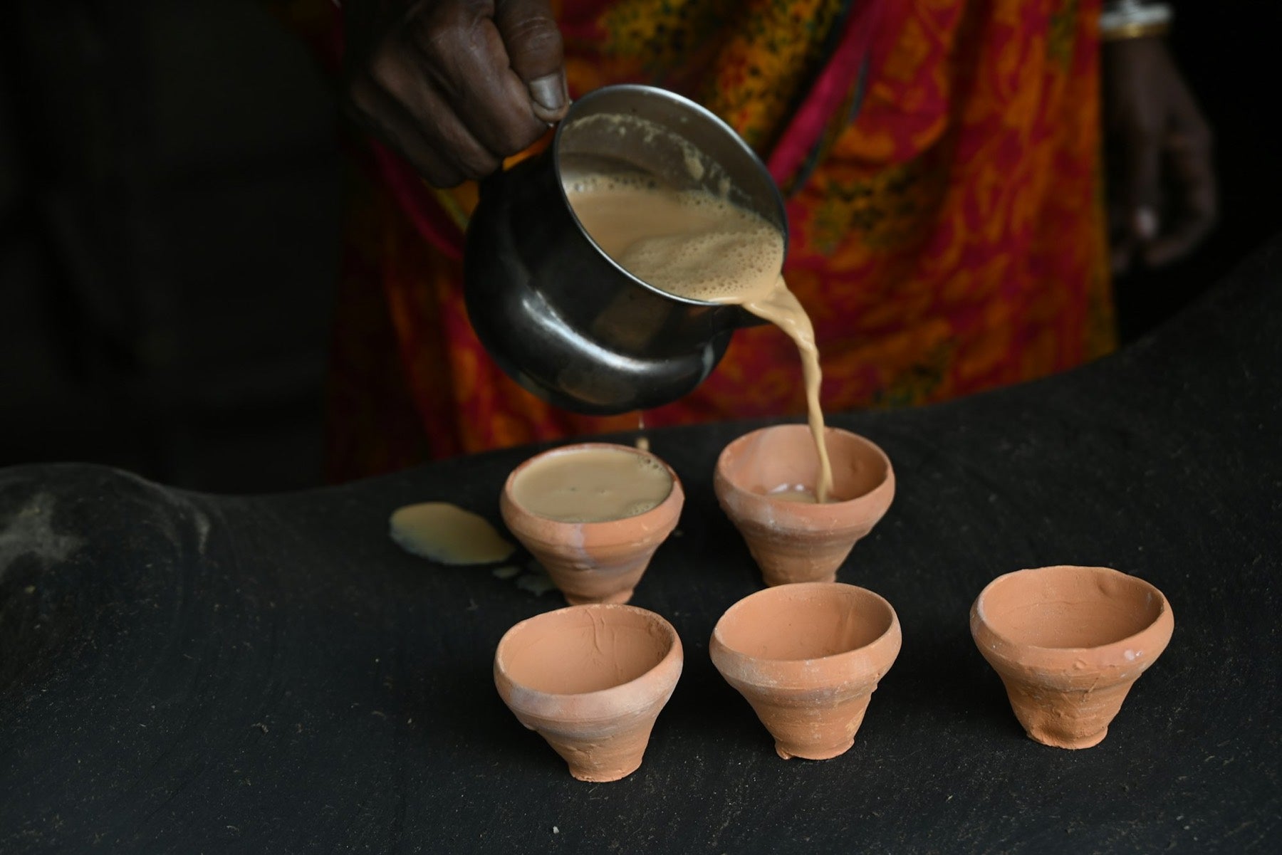 Masala chai being poured into clay cups