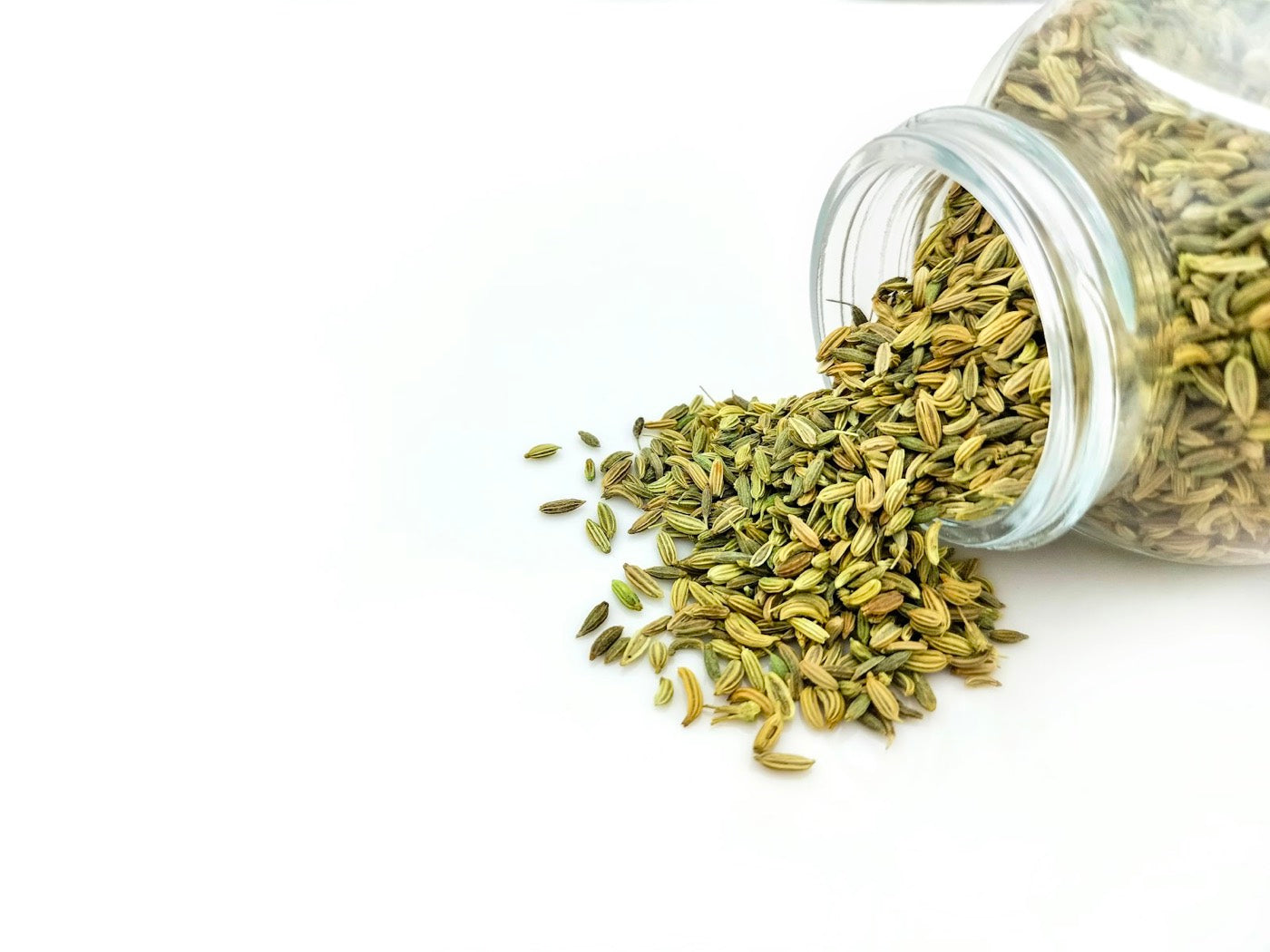 Coriander seeds spilling from a glass jar