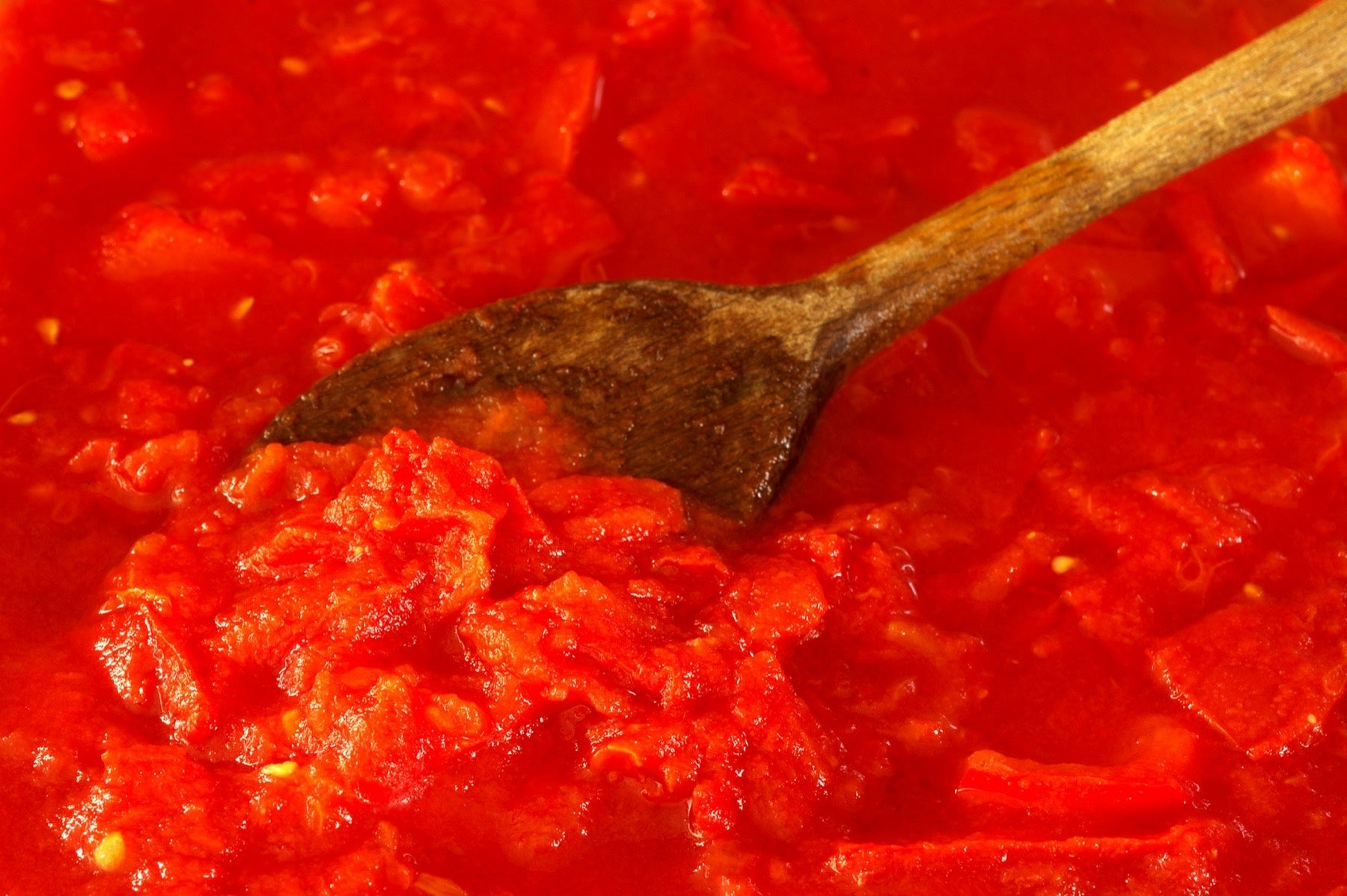 Tomato sauce simmering with a wooden spoon