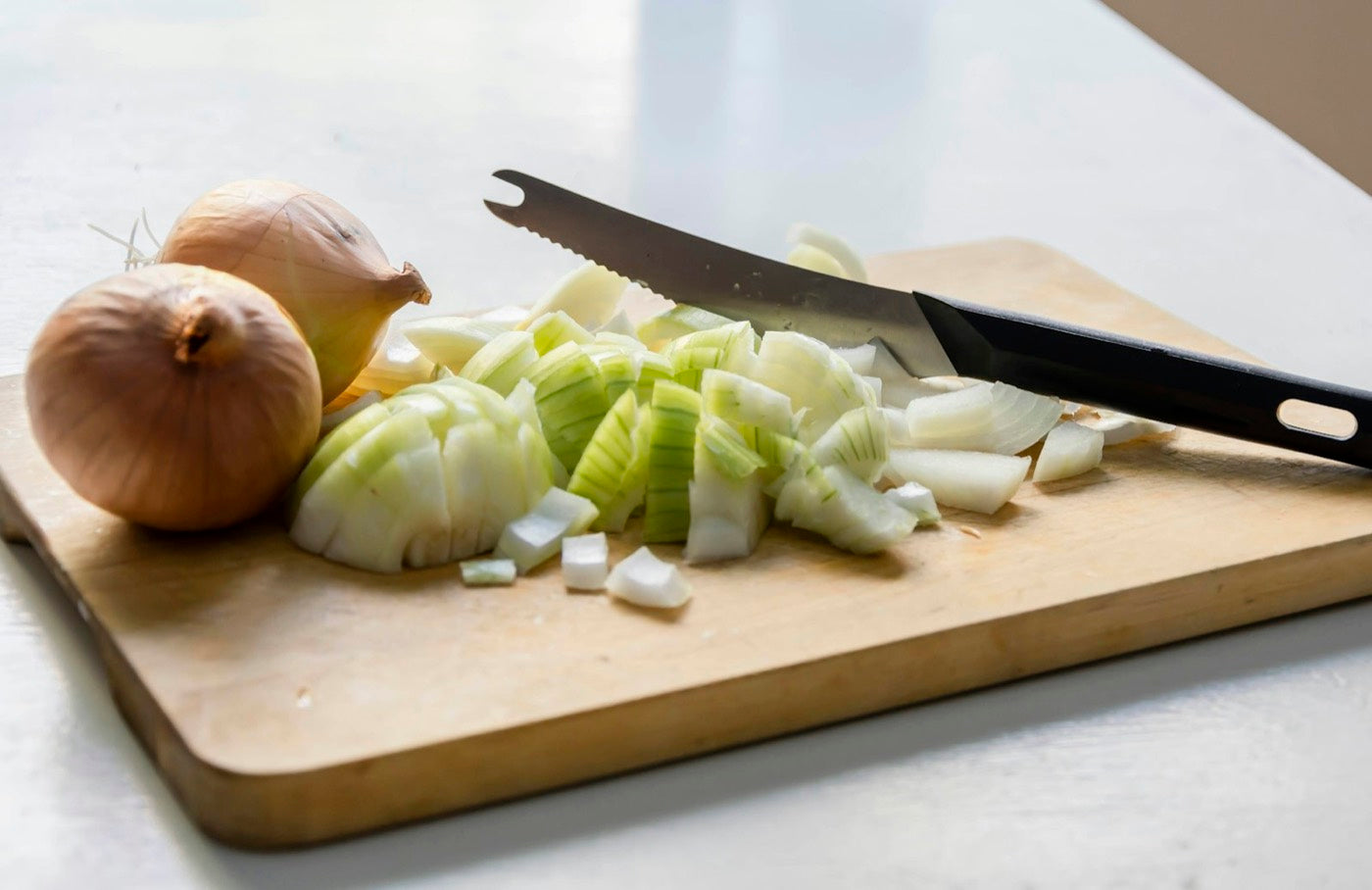 Chopped onions on a wooden board with a knife