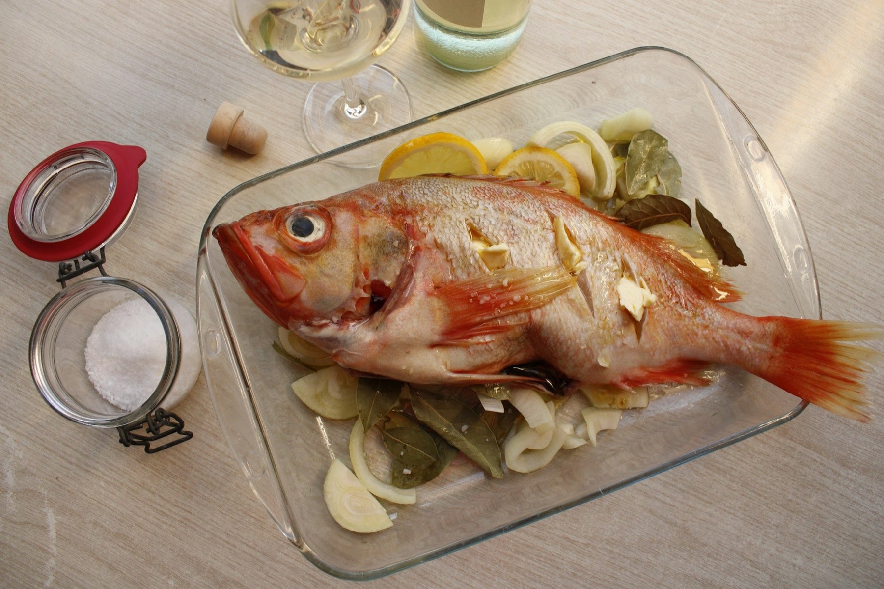 Poisson entier avec citron dans un plat en verre, prêt pour le four