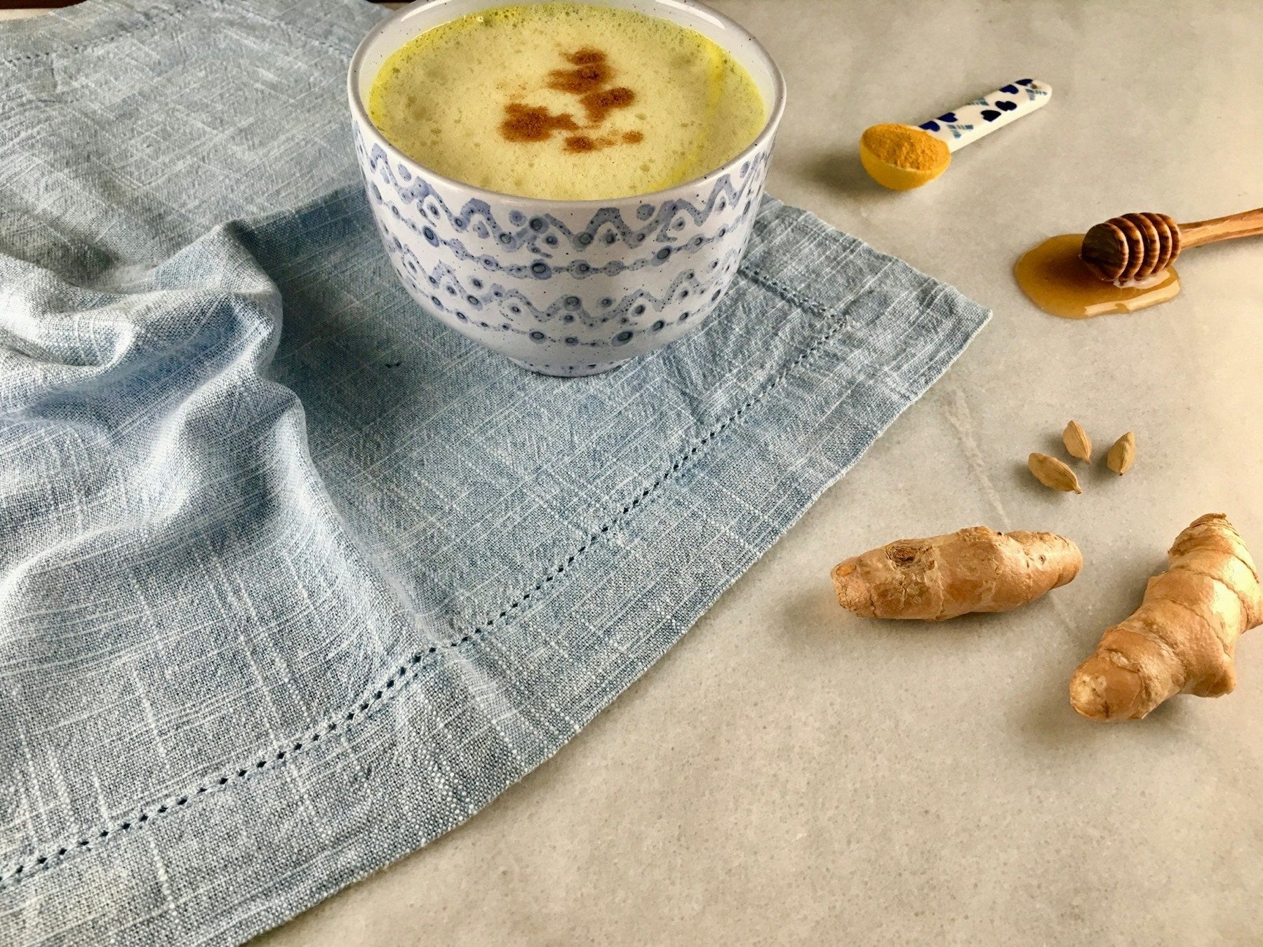 Golden milk in a cup with honey and turmeric root